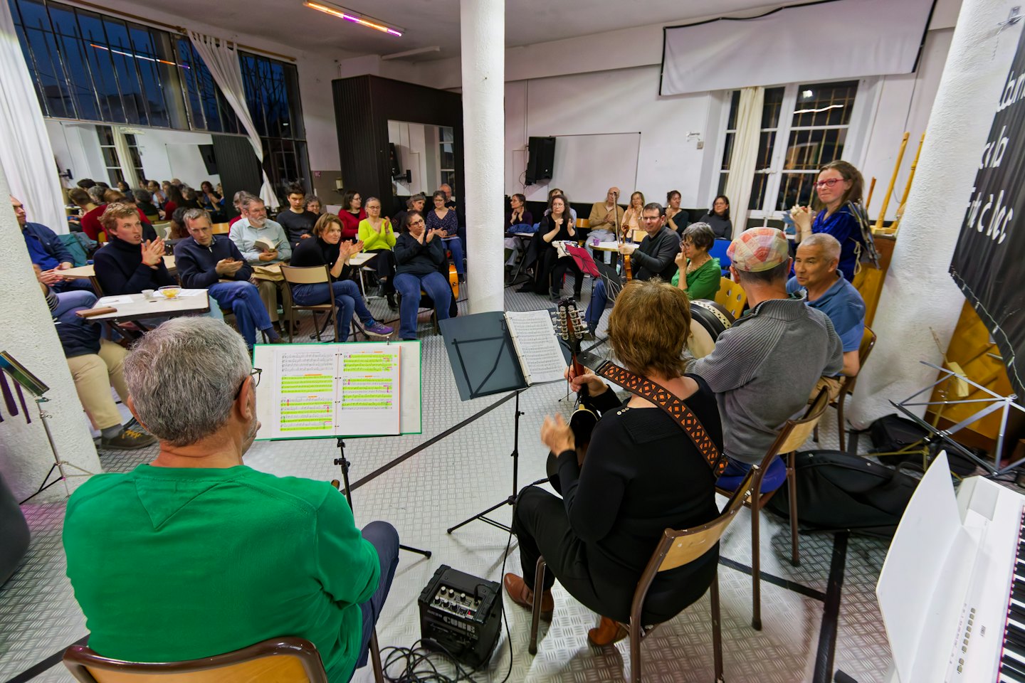 Persone suonano strumenti musicali mentre il pubblico applaude.