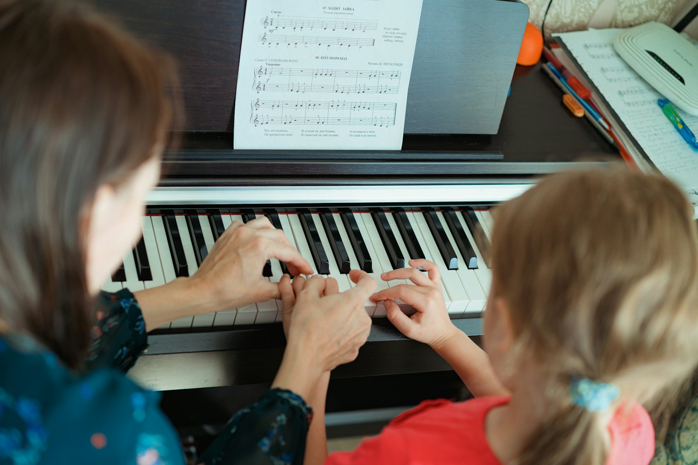 Un adulto insegna a un bambino a suonare il pianoforte.