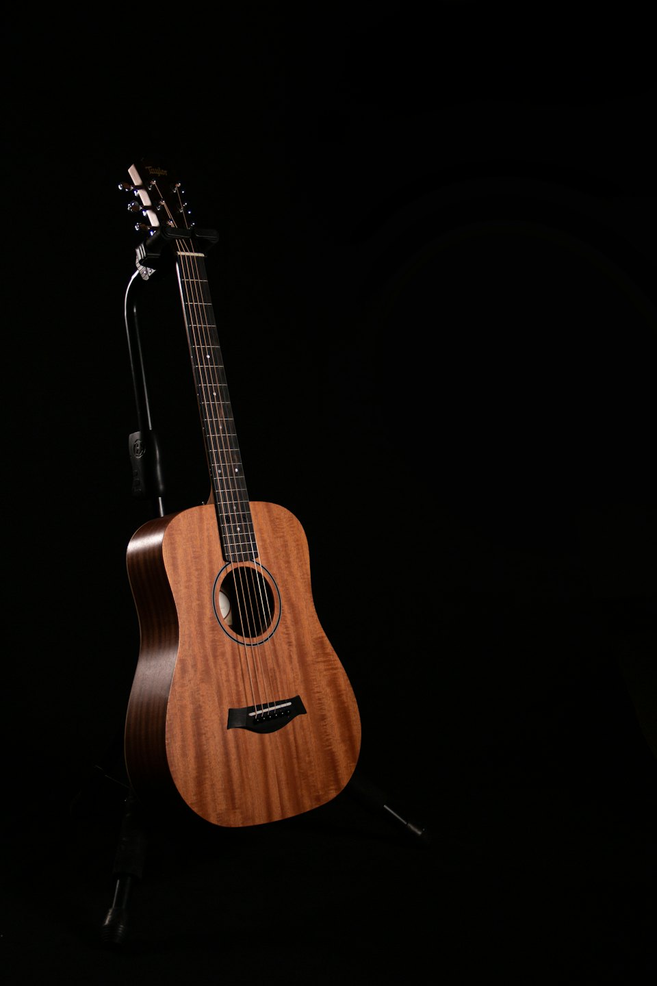 Una chitarra acustica poggia su un supporto nero da studio.