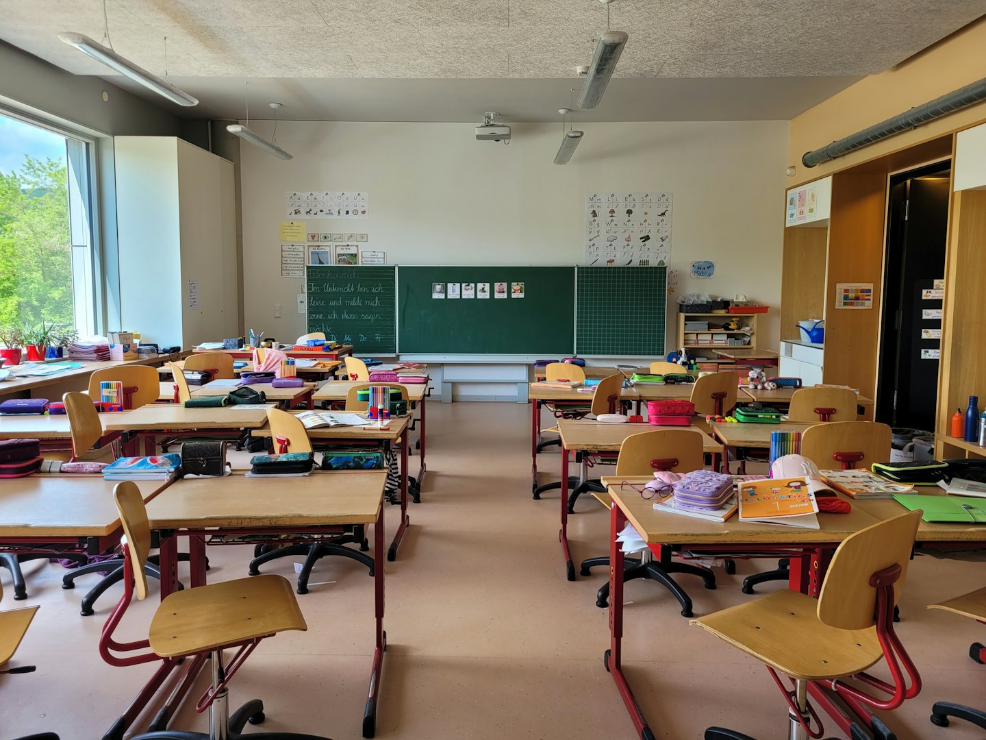 Aula moderna vuota con file di banchi e una lavagna.